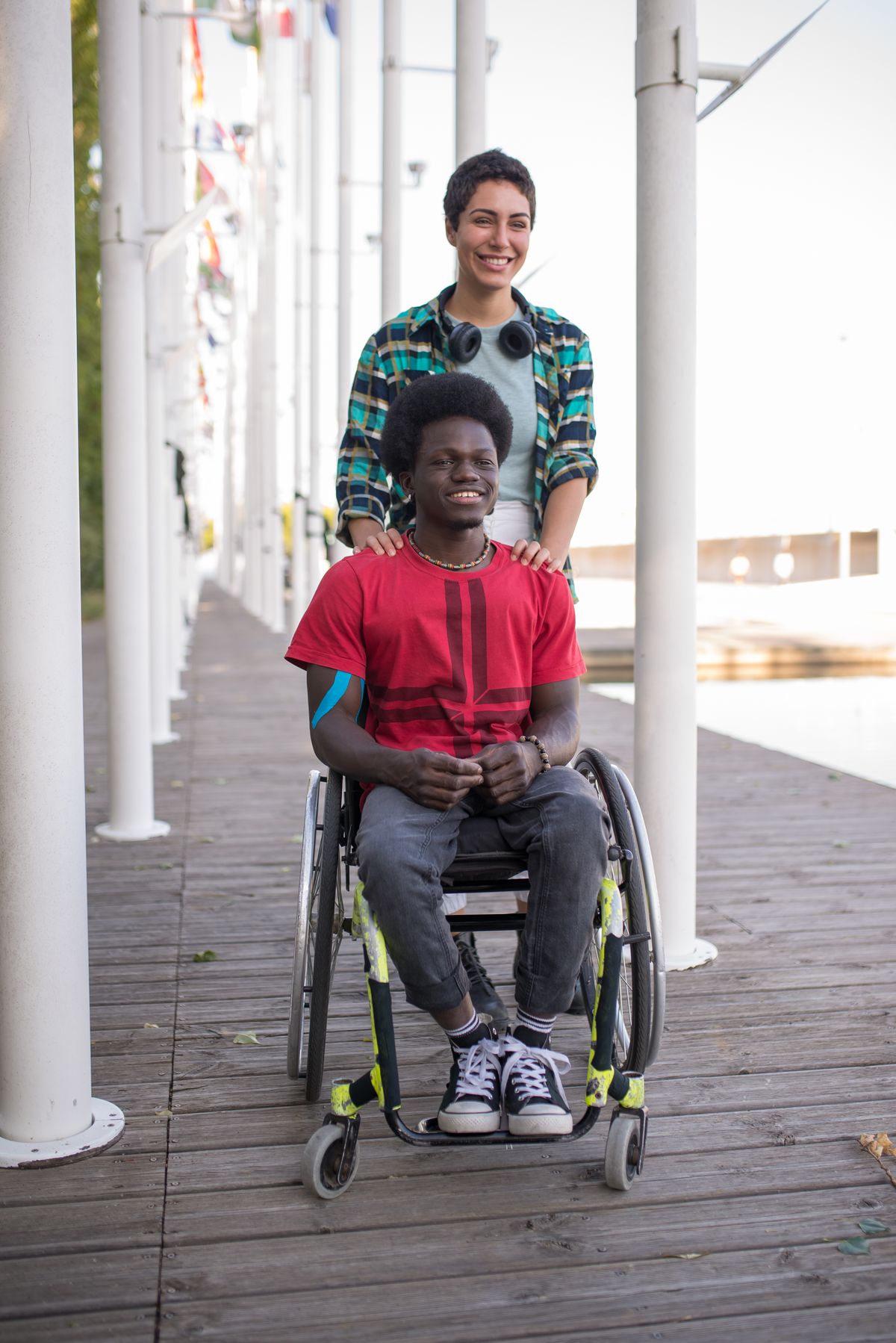 Two people laughing together outdoors, one using a wheelchair